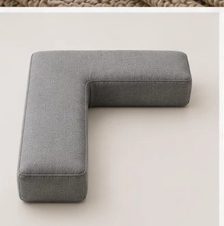 A single grey L-shaped Cradle pillow shown on its own, showing the clean L form and quilted cover